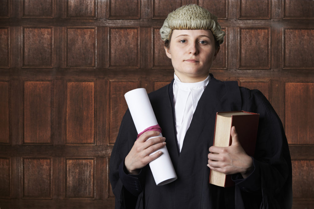 Portrait Of Female QC Lawyer In Court Holding Brief And Book